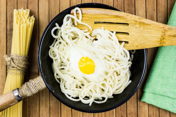 煎蛋和意大利面条在一个黑平底锅在木桌 在家做饭 乡下菜 — 图库照片