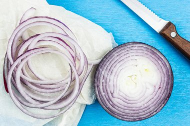 Yüzük mor soğan ve bir bıçak. Masa lambası üzerinde taze kırmızı soğan.