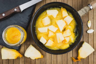 Ahşap bir masa üzerinde bir tavada kabak parçaları. Kabak yemek ev.