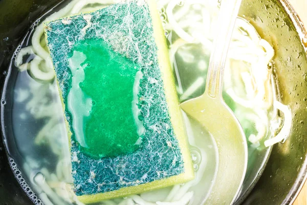 Sponge for washing dishes with green cleaning gel. The process of washing dishes, frying pans.