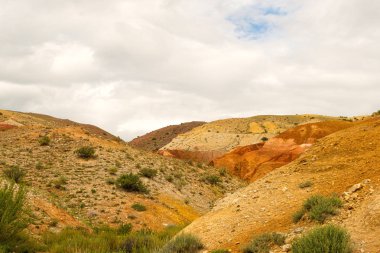 Dağ vadisindeki renkli tepeler. Sıcak yaz gününde kuru kumlu tepeler. Kuraklık, iklim değişikliği. Vadilerdeki toprak erozyonu