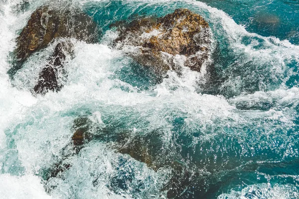 Mavi sularda taşlı bir dağ nehri. Turkuaz deniz gelgiti dalgaları