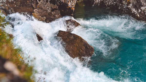 Rough river flow. The blue water of mountain river, the tide on sea with turquoise water and stone banks