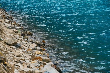 Mavi gölün kayalık kıyısı. Turkuaz deniz dalgaları kıyıya vurur