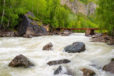 Dağ nehri üzerindeki ahşap köprü. Hızlı derenin üzerinden yayalar için geçiş.