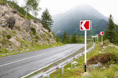 Dağ vadisindeki asfalt yolda ufukta kayalar var. Vahşi doğada arabayla rahat bir yolculuk.