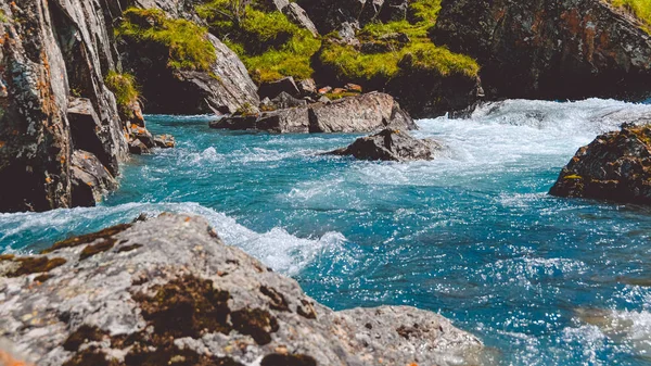 Taştan kıyısı olan nehirde turkuaz su. Deniz gelgiti, dağ deresinde kaynayan mavi su.