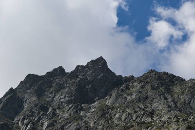 Mavi gökyüzünün altında bulutlu kayalar. Dağ yürüyüşü, yaz turizmi.