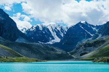 Dağ tepelerinin arasında turkuaz göl. Yaz günü yüksek dağ nehri, kayalar ve taşlar üzerinde yürüyüş.