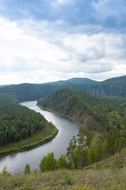 wide river between green hills, smooth bend of riverbed, contemplation of nature for meditation and relaxation