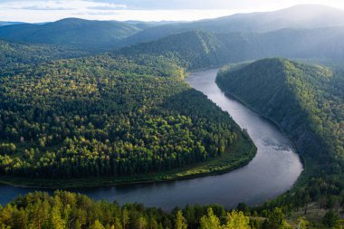 wide river between green hills, smooth bend of riverbed, contemplation of nature for meditation and relaxation