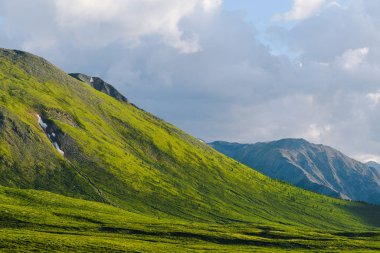 Mavi bulutlu gökyüzünün altındaki yeşil tepeler. Otlaklar için dağ vadisi
