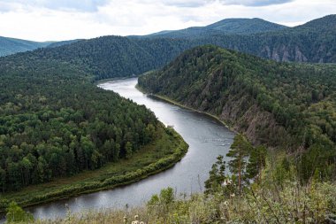 wide river between green hills, smooth bend of riverbed, contemplation of nature for meditation and relaxation