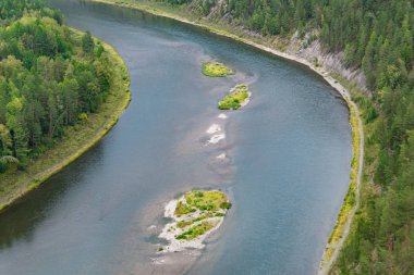 Ağaçlı yeşil tepelerin arasında geniş bir nehir, kanalın pürüzsüz kıvrımları, rezervuarın kıyısındaki orman, yaz yüzüşü ve seyrüsefer.