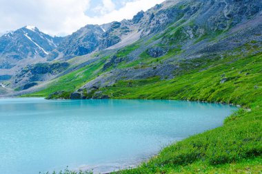 Dağ tepelerinin arasında turkuaz göl. Yaz günü yüksek dağ nehri, kayalar ve taşlar üzerinde yürüyüş.