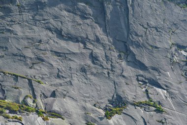 Arka planda çatlaklar ve çıkıntılar olan kaya duvarı, dağ tırmanışı ve dağcılık, dağın tepesine tırmanma