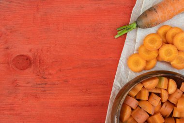 Kırmızı ahşap masada taze kesilmiş havuç dilimleri, sağlıklı yemek için vejetaryen salatası pişirmek.