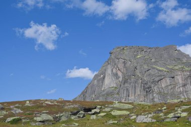 Mavi gökyüzünün altında bulutlar, kaya sırtına tırmanma hazırlığı, dağ vadisinde yolculuk