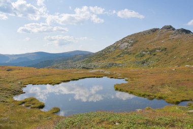 Kayaların altında göl, dağ vadisinde sonbahar yürüyüşü.