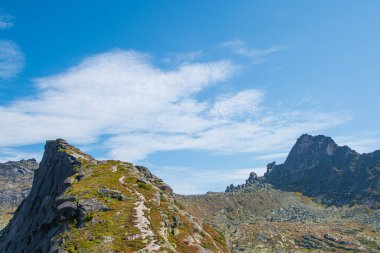 Mavi bulutlu gökyüzünün altındaki kaya sırtı, dağ turizmi, dinlenmek için turistik alan