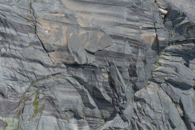 Arka planda çatlaklar ve çıkıntılar olan kaya duvarı, dağ tırmanışı ve dağcılık, dağın tepesine tırmanma