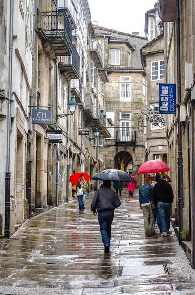 İnsanlar sokakta, eski şehir Santiago de Compostela, Galiçya, İspanya, 2011 şemsiye ile yağmurda yürümek
