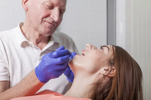 Dentista examina gengivas e dentes de sua paciente feminina — Fotografia de Stock