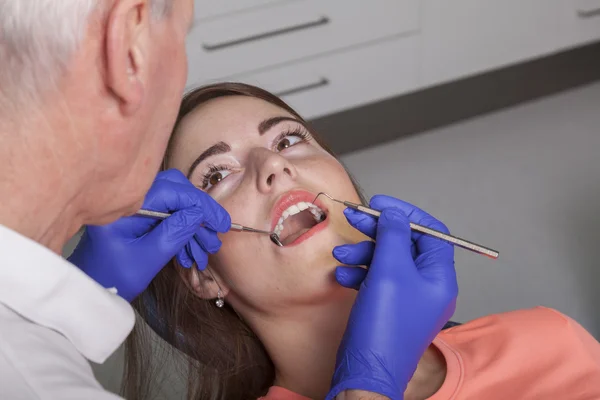 Zubní lékař kontroluje, dásně a zuby svého pacienta se zrcadlem a pro — Stock fotografie