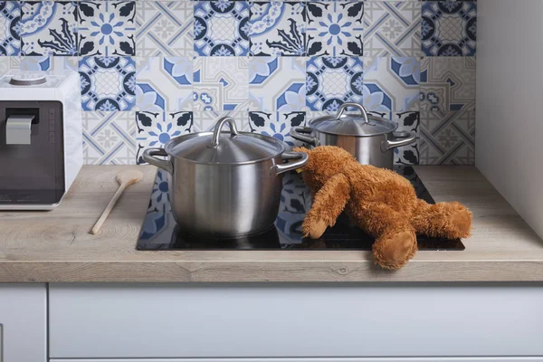 Brown teddy bear toy next to cooking pot on the hotplate in the kitchen — Stock Photo, Image