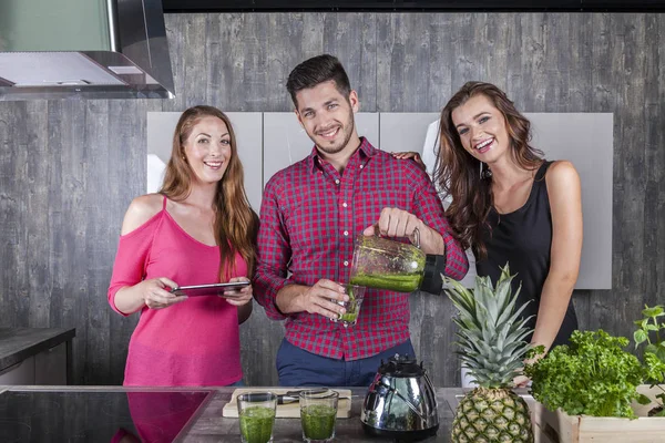 Amigos felices preparan batido verde en la cocina — Foto de Stock