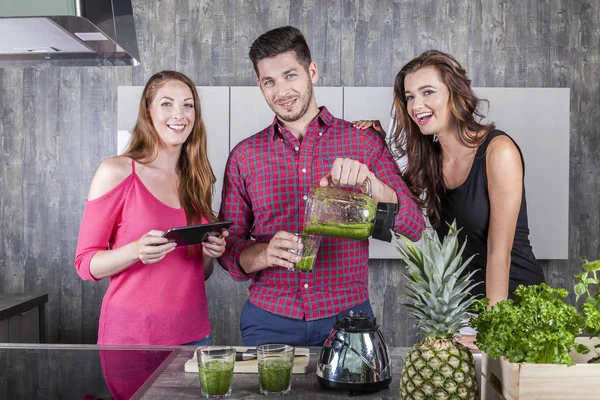 Vrienden in de keuken bereiden een gezonde groene smoothie drinken — Stockfoto