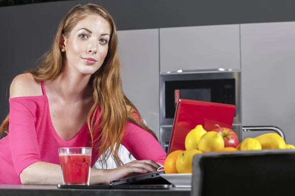 Mulher na cozinha com notebook laptop gerenciando receita de cozinha — Fotografia de Stock