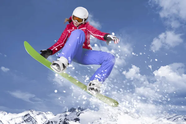 滑雪板在红色夹克和黄色长裤跳跃在她的滑雪板通过空气在山全景和冬天风景之前 — 图库照片