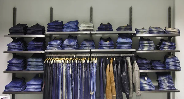 Jeans azules en estante y chaquetas — Foto de Stock