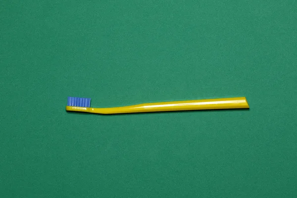 Cepillo de dientes amarillo sobre fondo verde — Foto de Stock