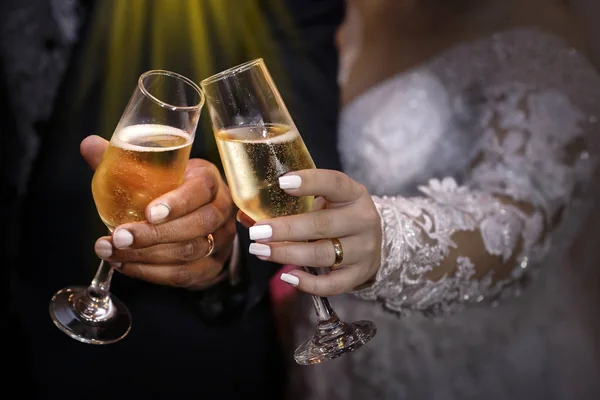 Hands with wedding rings holding champagne glasses
