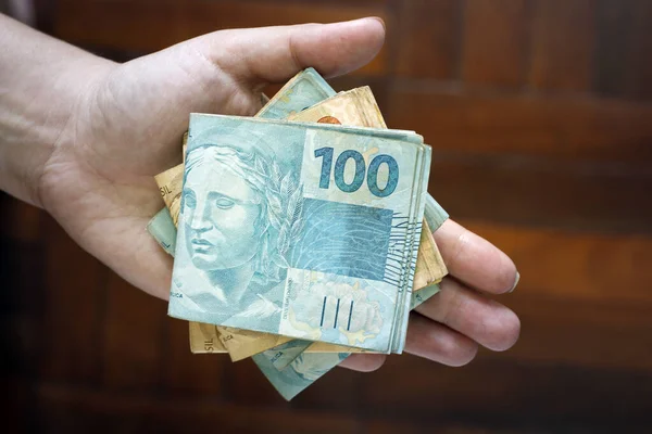 Hands holding Brazilian real notes, money from Brazil, notes of Real, Brazil BRL banknote, Brazilian currency, economy and business.