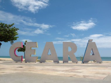 Brezilya 'nın Ceara eyaletinin Fortaleza şehrinde plaj ve denizde büyük renkli harflerle Ceara yazıtlarıyla turizm tabelasına varmak.