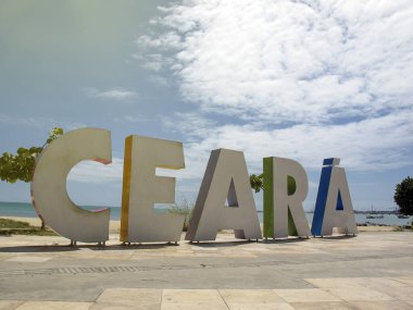 Brezilya 'nın Ceara eyaletinin Fortaleza şehrinde plaj ve denizde büyük renkli harflerle Ceara yazıtlarıyla turizm tabelasına varmak.