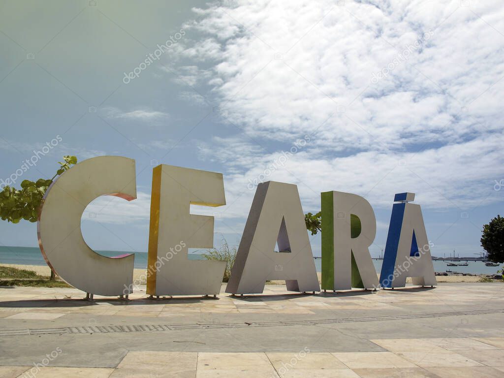 arriving signage tourism board with Ceara inscription in large, colorful letters on the beach and sea in the city of Fortaleza, state of Ceara, Brazil