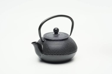 Beyaz zemin üzerinde siyah dökme demir çaydanlık.