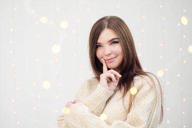 Beyaz arka planda süveter giyen esmer bir kadın. Duygularla portre. Neşe, mutluluk ve sürpriz.