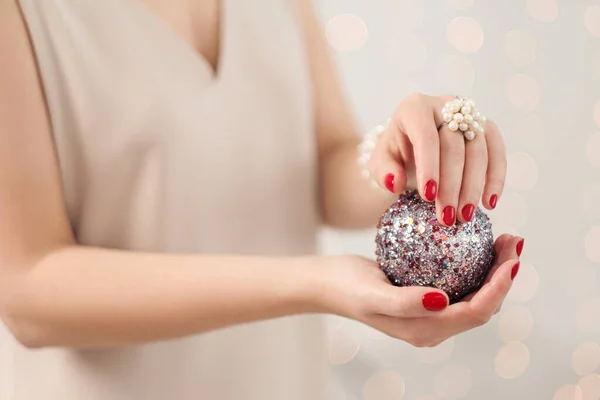 Christmas decoration, ball in female hands close-up. White background. — Stock Photo, Image