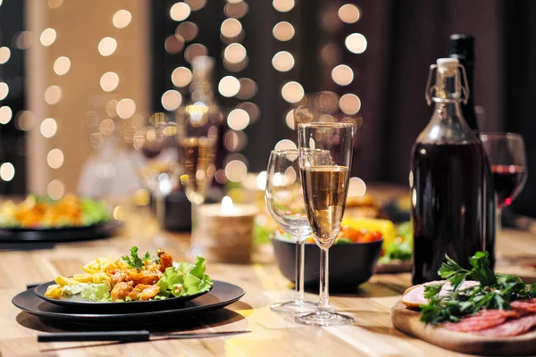 Kutlama masası. Yemek ve içecekler, tabaklar ve bardaklar. Akşam ışıkları ve mumlar. Yeni Yıl Arifesi.