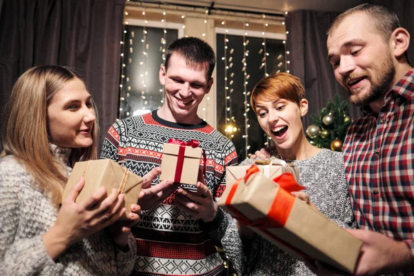 Um grupo de amigos, homens e mulheres, celebram o Natal. Eles dão presentes um ao outro, alegram-se e riem. Eva de Ano Novo . — Fotografia de Stock