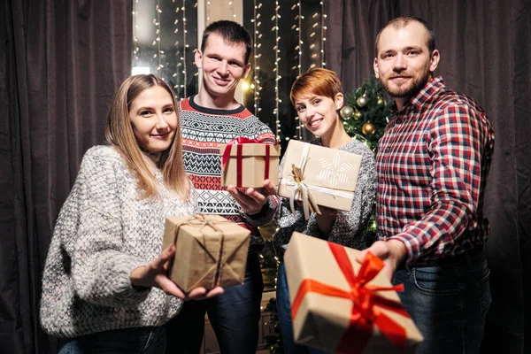 Eine Gruppe von Freunden, Männer und Frauen, feiern Weihnachten. Sie beschenken sich gegenseitig, freuen sich und lachen. Silvester. — Stockfoto