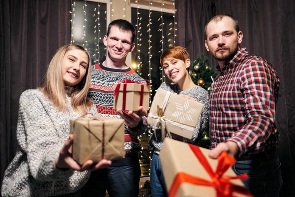 Um grupo de amigos, homens e mulheres, celebram o Natal. Eles dão presentes um ao outro, alegram-se e riem. Eva de Ano Novo . — Fotografia de Stock