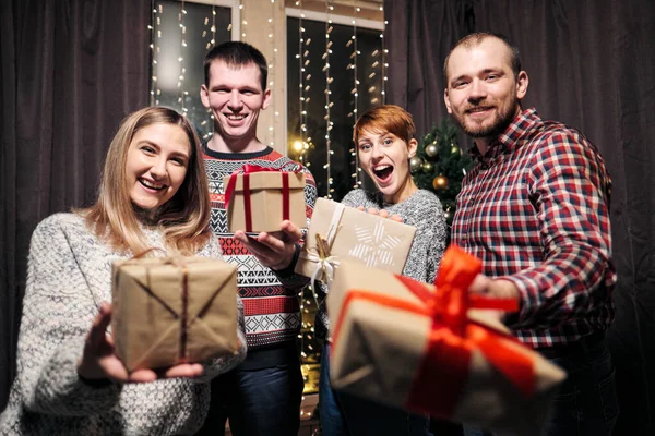 Um grupo de amigos, homens e mulheres, celebram o Natal. Eles dão presentes um ao outro, alegram-se e riem. Eva de Ano Novo . — Fotografia de Stock