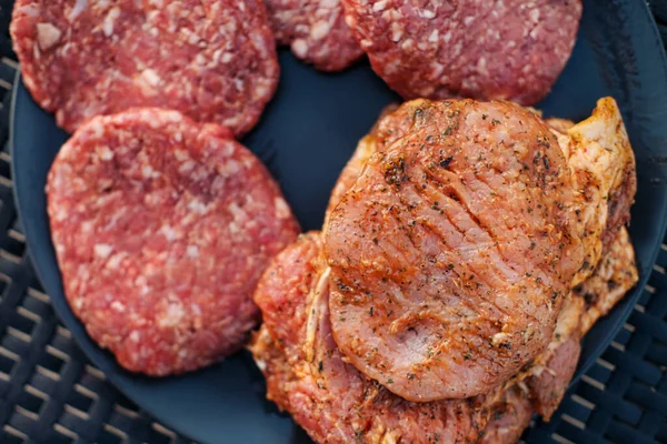 Churrasqueira. Um homem frita bifes de carne e almôndegas para hambúrgueres, vira a carne com pinças. . — Fotografia de Stock