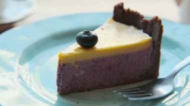 Camın yanındaki sıcak bir kafede, bir fincan çay ve bir tatlı yaban mersinli cheesecake ile yakın plan..